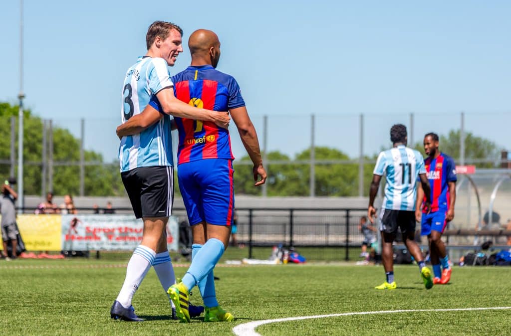 Voetballers lopen zij aan zij over het voetbalveld